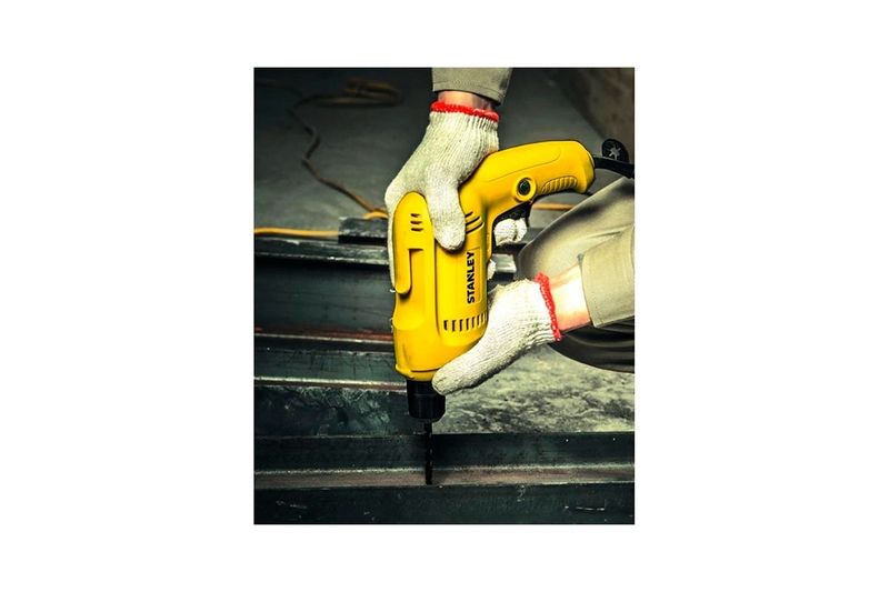Taladro rotación eléctrico Stanley de 3/8 pulgadas y 550 W, siendo utilizado por una persona con guantes sobre metal