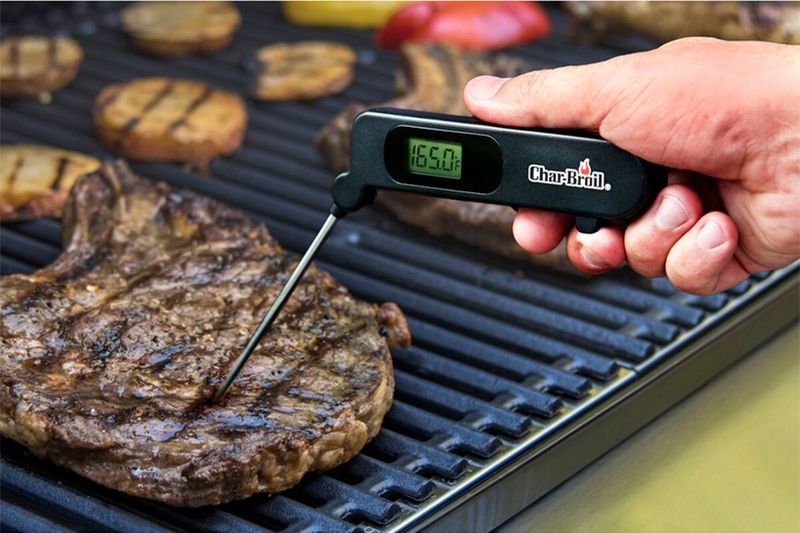 Termómetro digital acero inoxidable negro Char-Broil, mano usando el equipo para medir la temperatura de un corte de carne