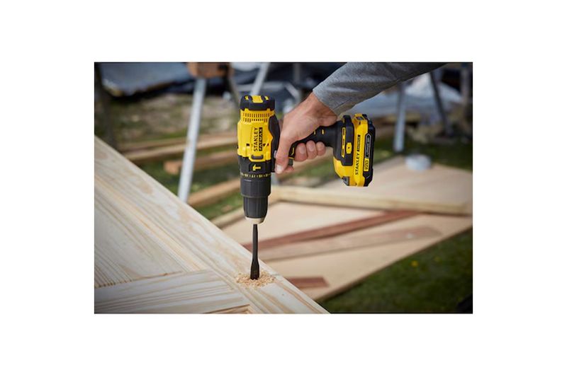 Taladro inalámbrico 1/2 pulgada V20 Stanley, siendo utilizado por una mano para perforar una pieza de madera clara