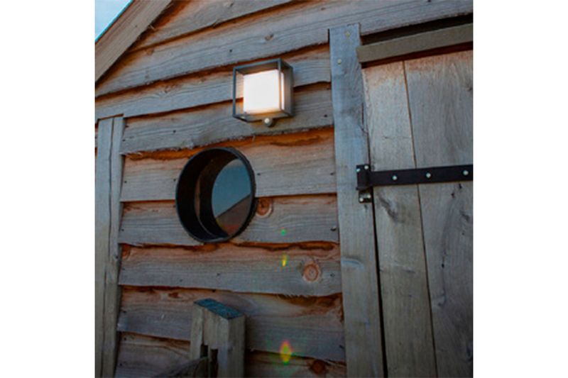 Luminaria pared exterior LED Ofelia con sensor y panel solar 3 W 300 lm 3000 K IP54 Tecnolite, encendida en pared de madera
