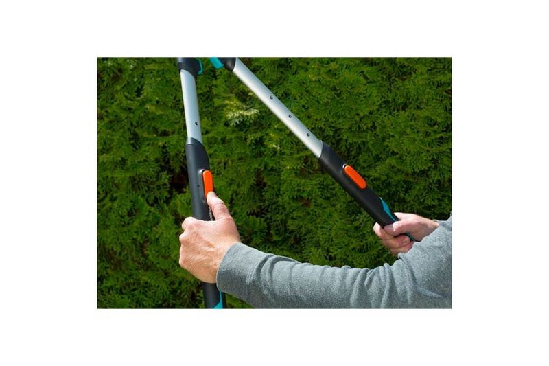 Tijera cortasetos mango telescópico 700 T Confort Gardena, detalle de las manos sujetando los mangos mientras corta un seto