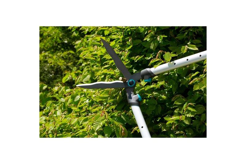 Tijera cortasetos mango telescópico 700 T Confort Gardena, primer plano de las cuchillas cortando follaje verde