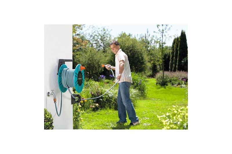 Portamanguera pared 60 m con guía dual fijo/portátil 2650-20 Gardena, hombre usando la manguera verde en un jardín