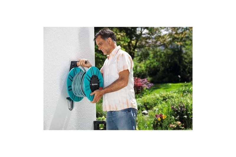 Portamanguera pared 60 m con guía dual fijo/portátil 2650-20 Gardena, hombre sosteniendo el equipo instalado en la pared