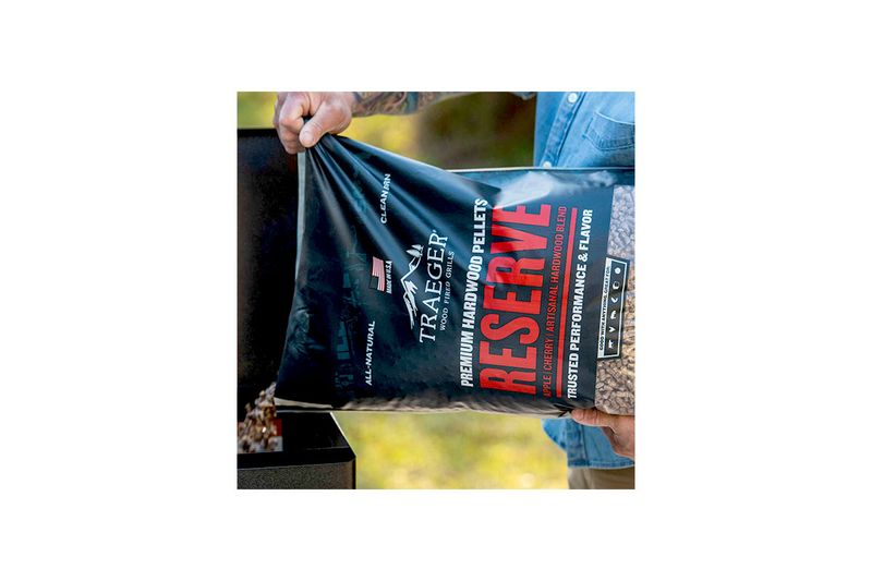 Pellets de madera manzana-cerezo-roble 20 lb Traeger, persona vertiendo el contenido de la bolsa en una parrilla