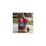 Pellets de madera cherry 20 lb Traeger, bolsa cerrada apoyada en el suelo junto a una parrilla Ironwood 885