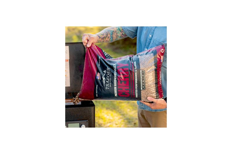 Pellets de madera cherry 20 lb Traeger, persona vertiendo el contenido de la bolsa en la tolva de una ahumadora