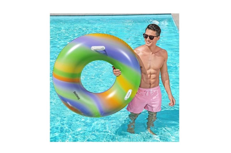 Flotador ring rainbow 47 pulgadas Bestway, hombre sosteniendo el aro inflable multicolor dentro de una piscina