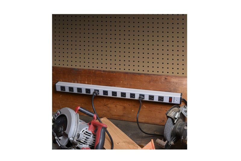 Regleta eléctrica 12 salidas color silver Monster, instalada en pared con dos herramientas eléctricas conectadas