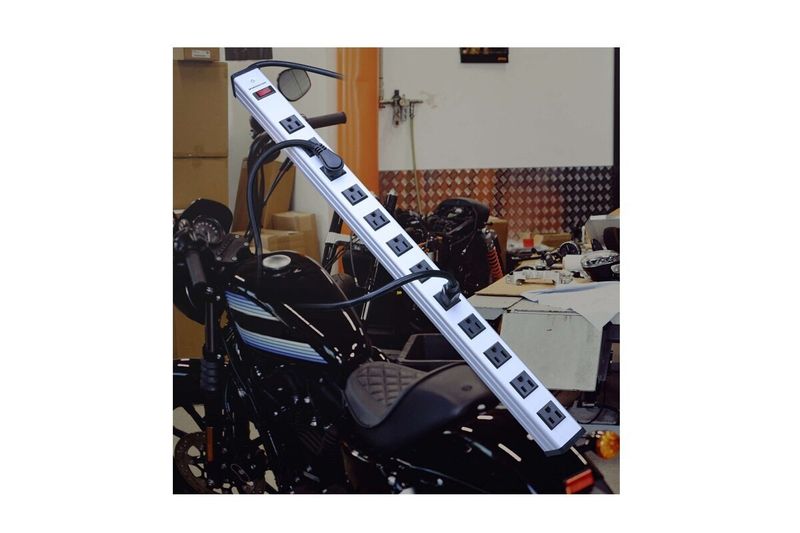 Regleta eléctrica 12 salidas Monster color silver, vista lateral apoyada sobre una motocicleta negra