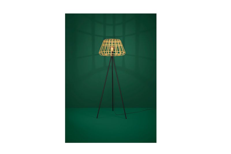 Luminaria de piso Montezuelo 1 luz E27 Eglo, encendida sobre fondo verde oscuro con trípode negro y pantalla de mimbre
