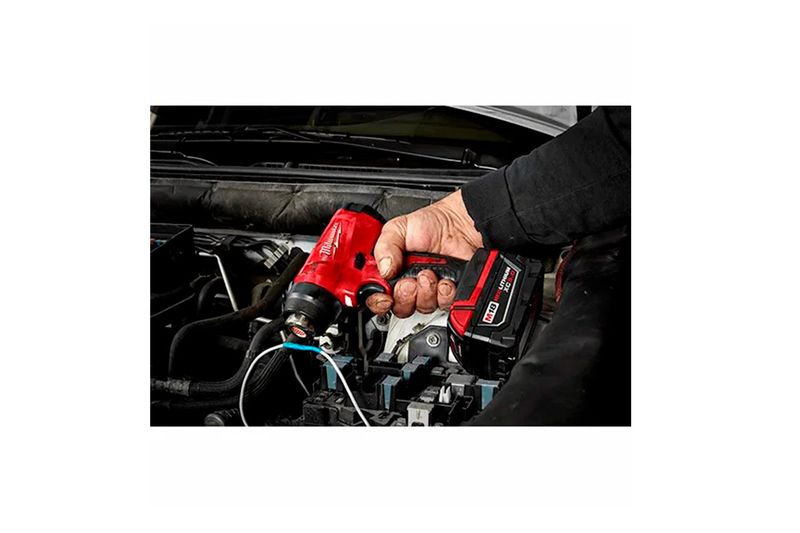 Pistola de calor inalámbrica M18 sin batería Milwaukee, siendo utilizada por una persona en el motor de un vehículo