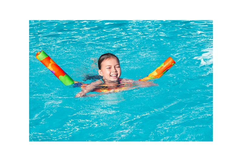 Flotador fideo de espuma Sugarcoated 48 6-12 años Bestway, niña sonriendo mientras flota en una piscina con el equipo