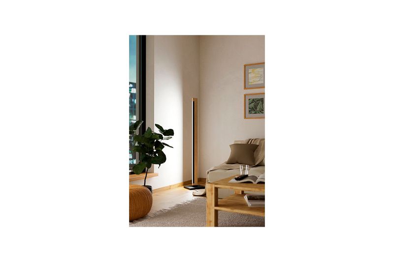 Lámpara de piso LED Camacho negro/madera Eglo, ambientada en una sala junto a un sofá y una planta