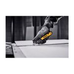 Navaja plegable DeWALT de 31 mm, mano con guante amarillo y negro realizando un corte sobre una superficie blanca