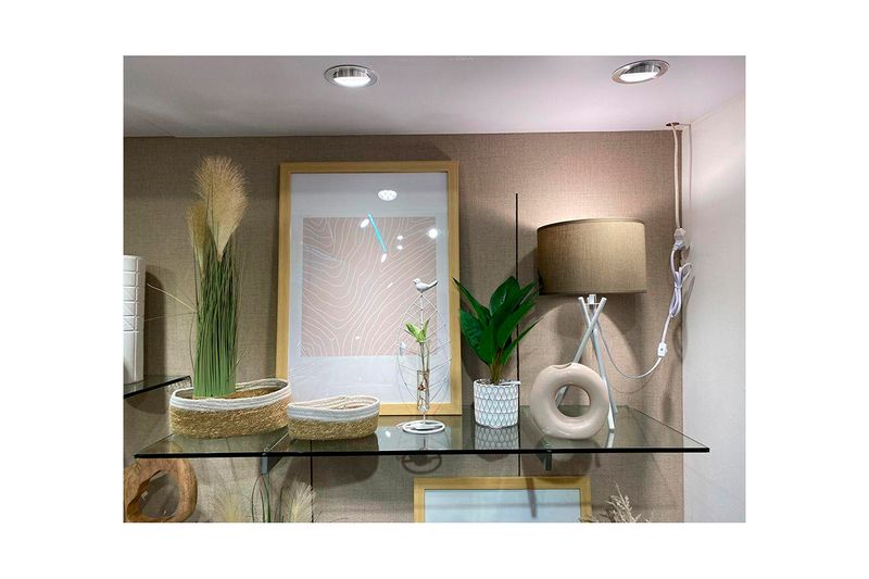 Lámpara de pedestal Paola 41 cm de tela bronce/blanco Concepts, ubicada sobre repisa de vidrio con decoración de interior