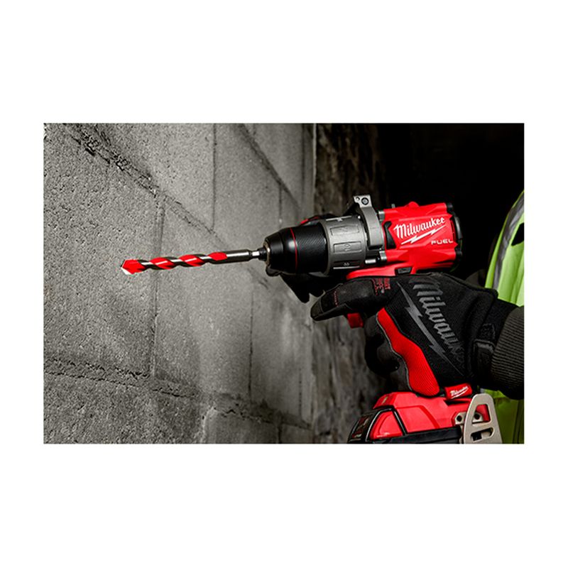 Broca de carburo Milwaukee de 1/2 x 4 pulgadas para concreto, instalada en un taladro rojo perforando una pared de bloques