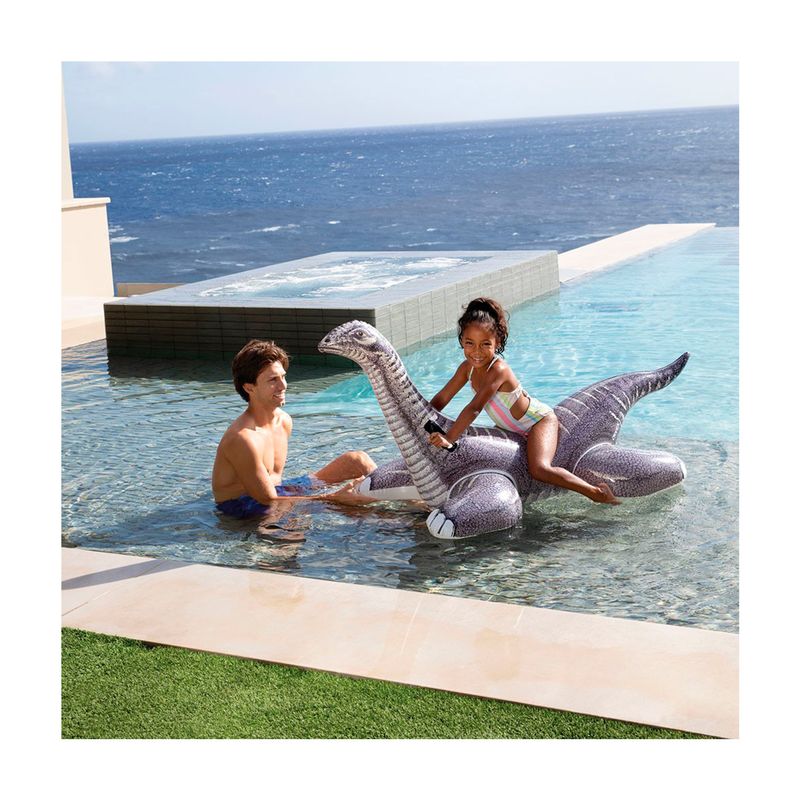 Flotador brontosaurio 1.78 x 0.94 m Intex, niña sentada sobre el inflable gris en una piscina infinita frente al mar