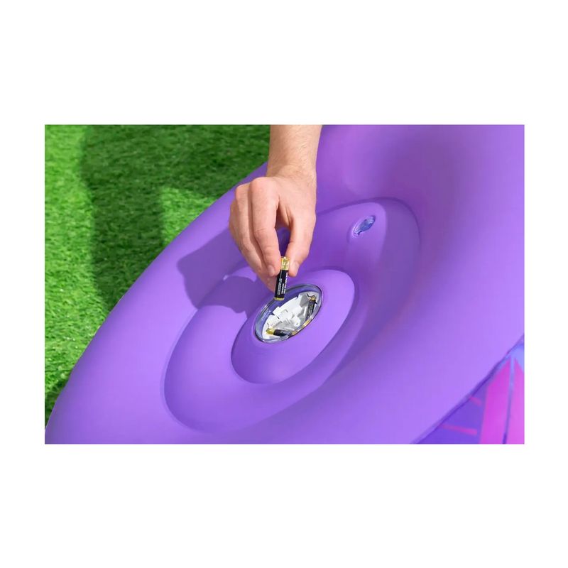 Sillón inflable para niños Astro Glow LED Bestway, detalle de mano insertando pilas en el compartimento del inflable morado