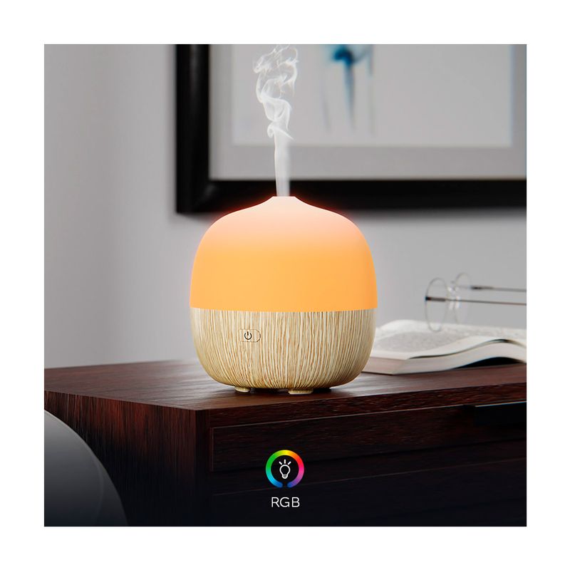 Difusor Mini Smart Nexxt, encendido con luz naranja y vapor saliendo, sobre una mesa de madera junto a un libro