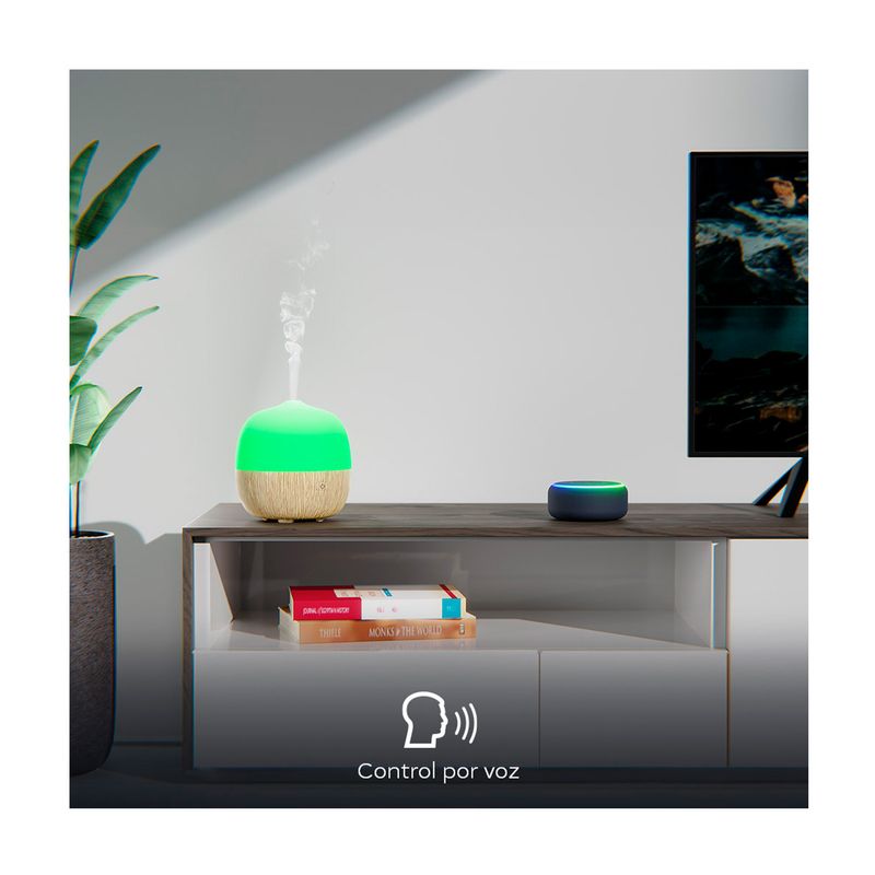 Difusor mini smart Nexxt, ambientado en una sala sobre un mueble con luz verde, emitiendo vapor y control por voz