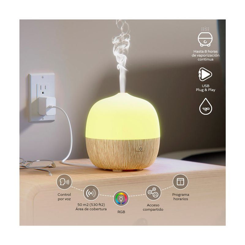Difusor mini smart Nexxt, encendido con luz amarilla y vapor saliendo, conectado a la corriente con cable USB blanco