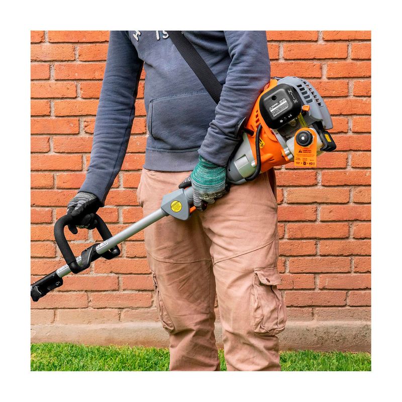 Desbrozadora gas 30 CC 17 pulgadas curva Truper, persona sosteniendo la máquina con el motor naranja al hombro