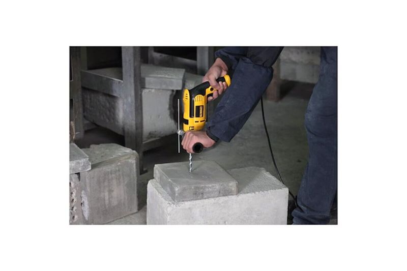 Taladro percutor eléctrico DeWalt de 1/2 pulgada y 650 W, siendo utilizado por una persona para perforar un bloque de