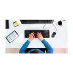 Dúo de mouse y teclado multimedia XTK-301S idioma español Xtech, vista cenital de una persona usándolos frente a un monitor