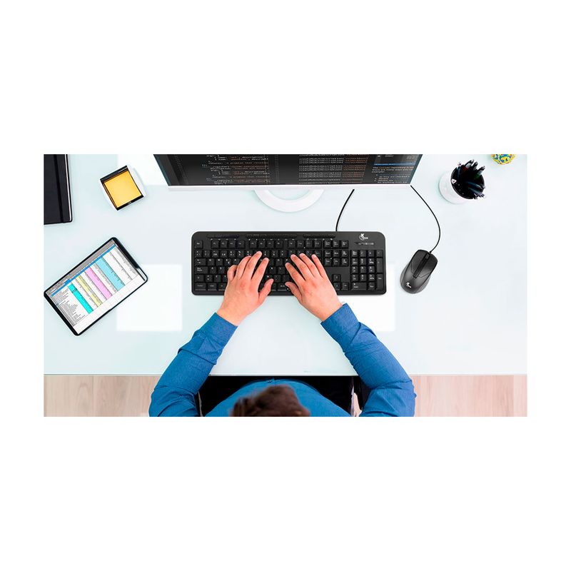 Dúo de mouse y teclado multimedia XTK-301S idioma español Xtech, vista cenital de una persona usándolos frente a un monitor