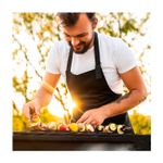 Barbacoa de carbón con ruedas 46 cm Koopman, hombre con delantal negro cocinando brochetas de vegetales al aire libre
