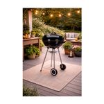 Barbacoa de carbón con ruedas 46 cm Koopman, ambientada en un patio exterior sobre una alfombra con luces decorativas