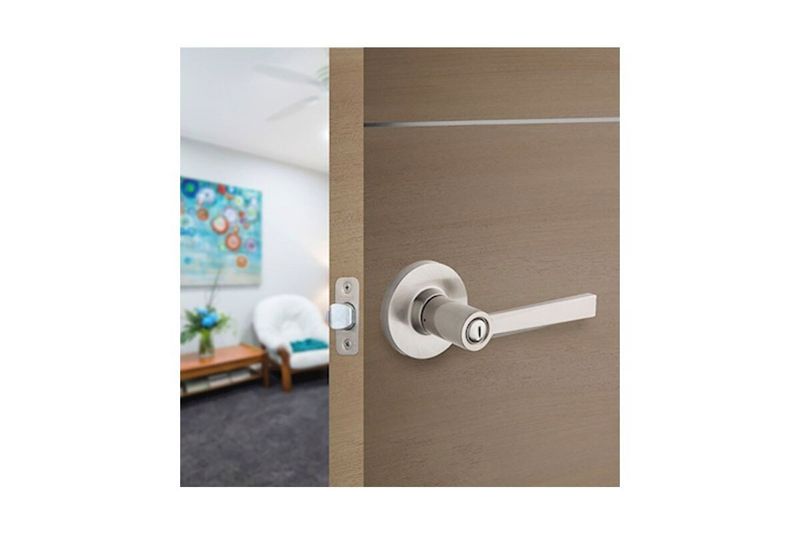Cerradura manecilla baño Westley satín níquel Kwik, instalada en puerta de madera color café con manija extendida