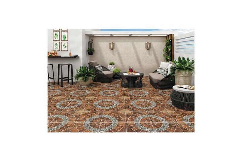 Baldosa 44x44 rojo geométrico Porcelanite, instalada en un piso de terraza con muebles de exterior y plantas