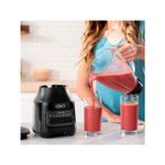 Licuadora vaso vidrio 1.5 L 800 W 6 vel gris Oster, vertiendo batido rojo en dos vasos de vidrio