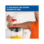 Licuadora vaso vidrio 1.5 l 800 w 6 vel gris Oster, detalle de mano vertiendo líquido con cuchara medidora de 60 ml