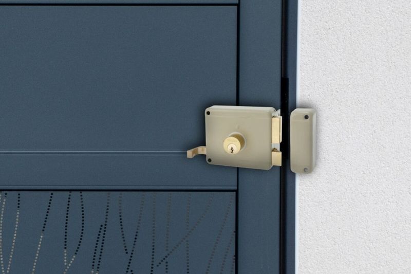 Cerradura parche 50 mm Toledo metal/madera cilindro suelto derecha, instalada en puerta azul con el pestillo extendido
