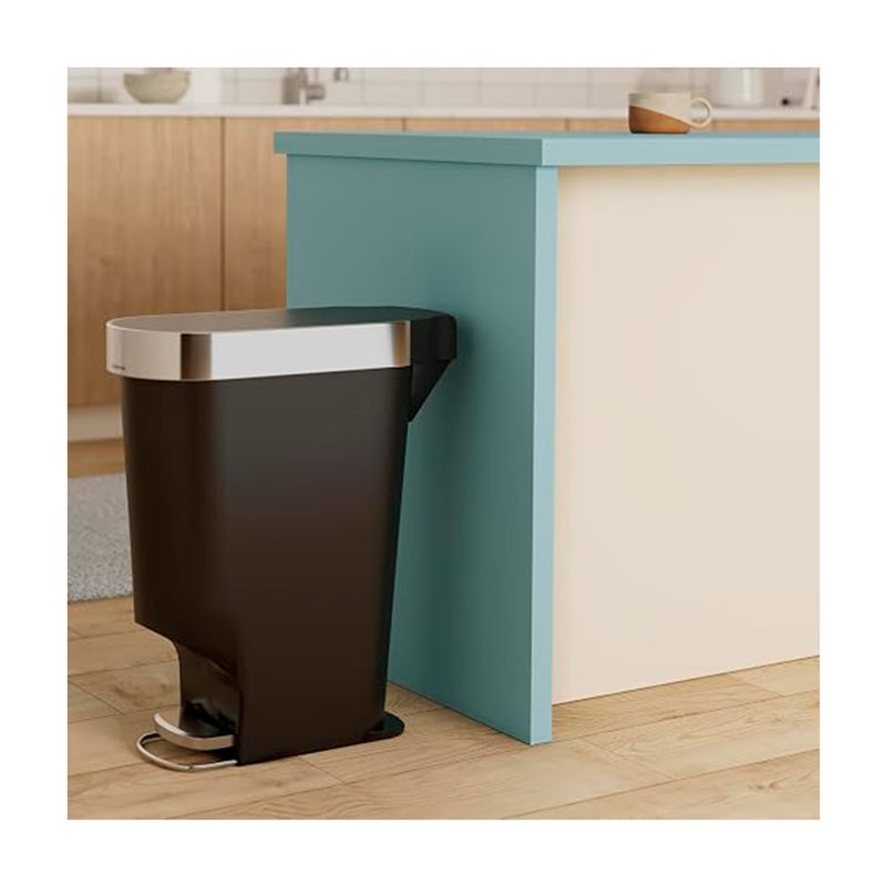 Basurero 40 L plástico negro Simplehuman, ubicado junto a un mueble de cocina color celeste