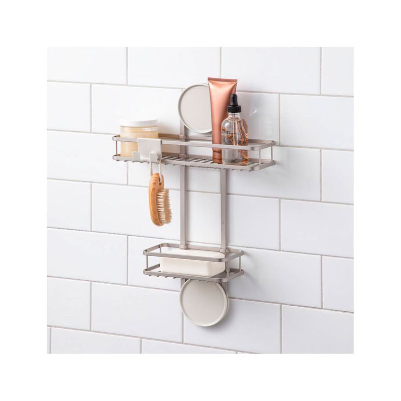 Organizador de ducha 2 niveles aluminio iDesign, instalado en pared blanca con artículos de aseo y cepillo de madera