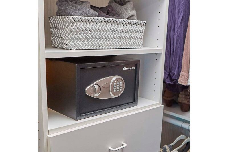 Caja de seguridad digital Sentry Safe de 0.5 pies cúbicos, colocada dentro de un estante blanco junto a una canasta