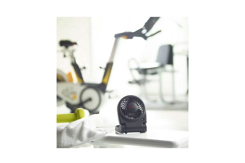 Abanico portátil Turbo-on-the-go USB y/o baterías AA Honeywell, en uso sobre una mesa blanca en un gimnasio
