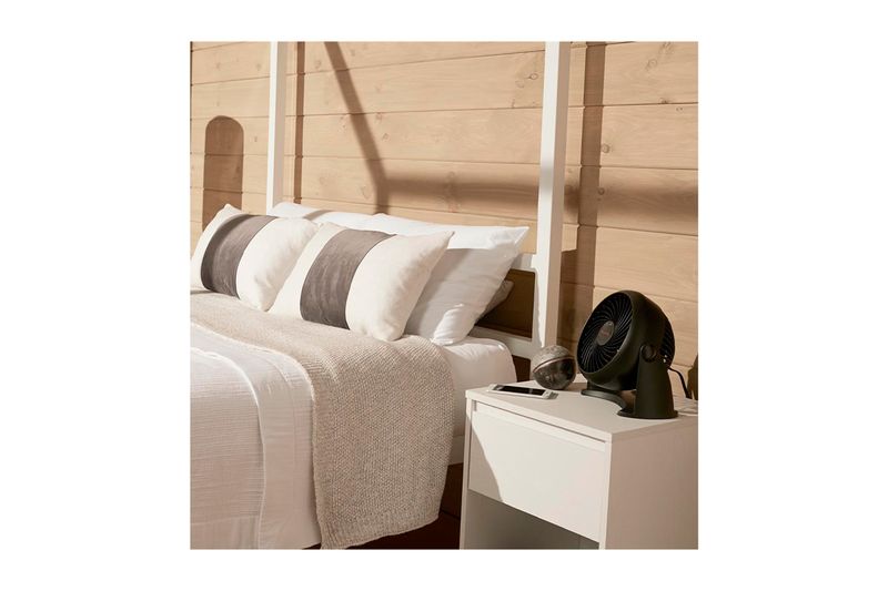Abanico de mesa Turbo Force 3 velocidades negro Honeywell, colocado sobre una mesa de noche junto a una cama