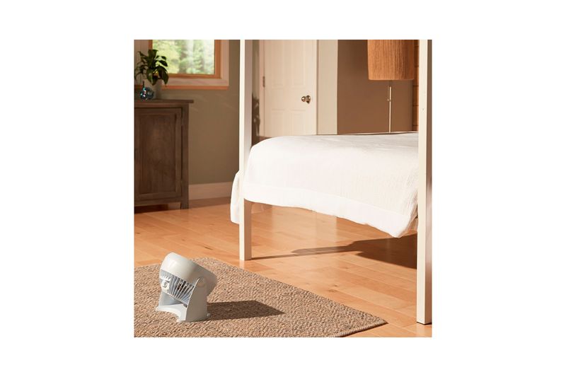 Abanico de mesa Turbo Force 3 velocidades blanco Honeywell, colocado en el suelo sobre una alfombra junto a una cama