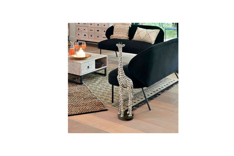 Figura decorativa jirafa 89 cm Atmosphera, ambientada en sala junto a sofá negro y mesa de centro