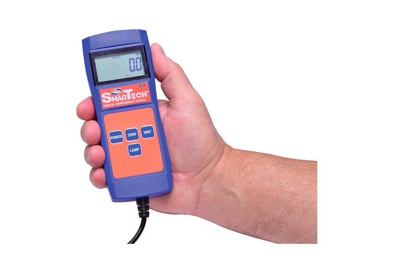 Báscula digital para cargar de refrigerante 220 lb Uniweld, control remoto azul sostenido por una mano