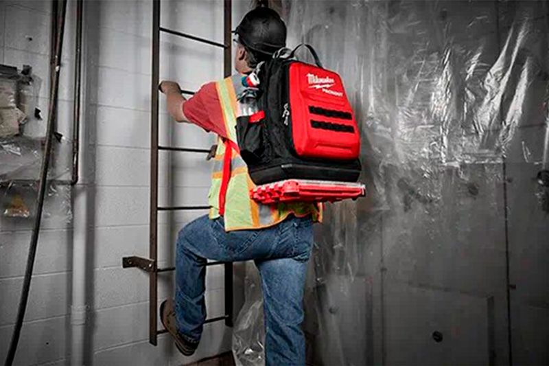 Mochila Packout 48 bolsillos Milwaukee, vista trasera de un trabajador usándola con una caja acoplada en la base