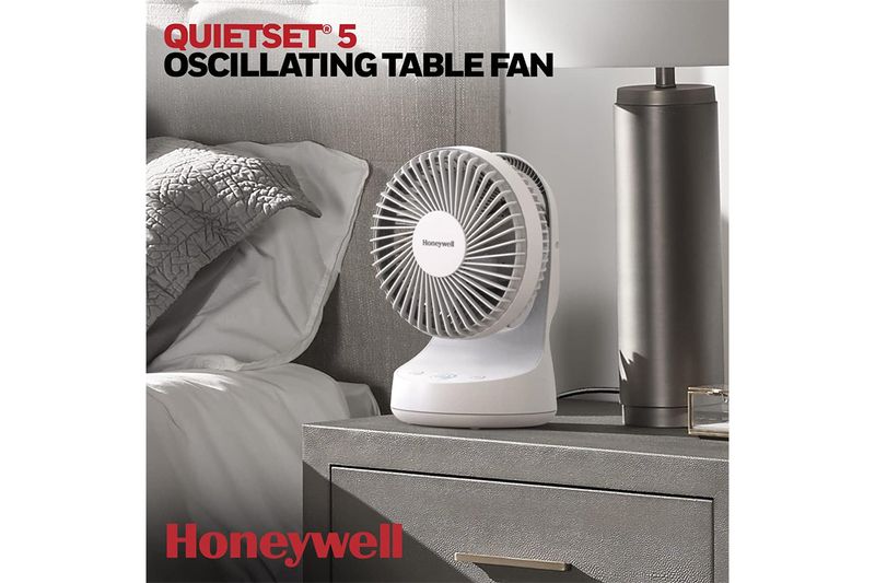 Abanico de mesa oscilante QuietSet 5 HTF337W Honeywell, colocado sobre una mesa de noche junto a una lámpara
