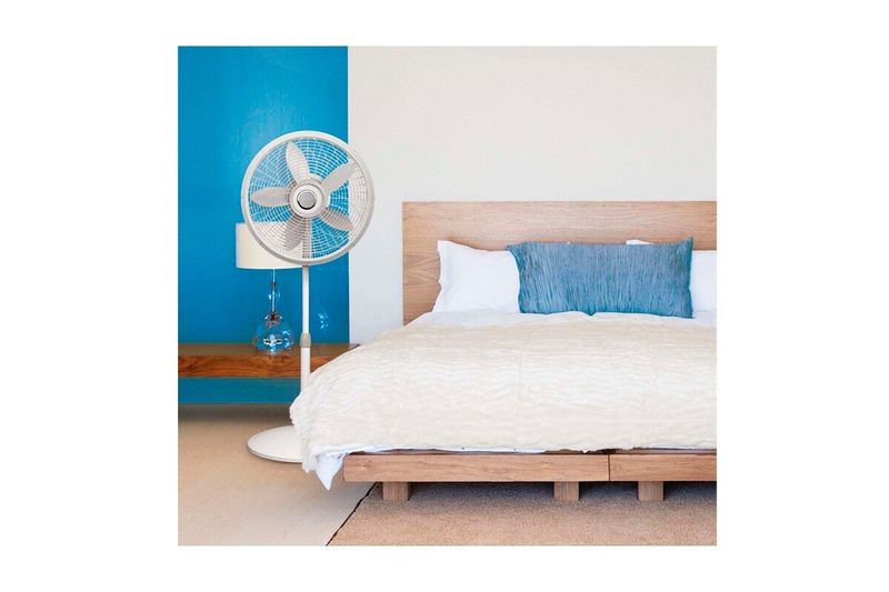 Abanico de pedestal 18 pulgadas 3 velocidades modelo M1820 blanco Lasko, ubicado en una habitación junto a una cama