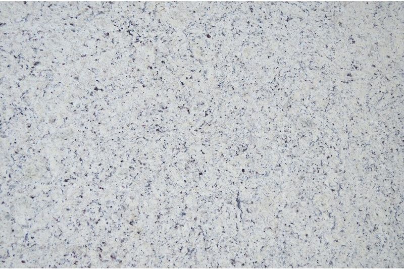Granito brasileño 2 cm White Dallas Sinsa, primer plano de la superficie con motas grises y negras sobre fondo blanco