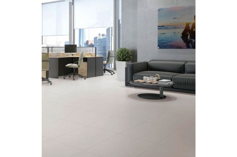 Baldosa 50x50 Portland Plus gris satinado Pisoforte, instalada en el piso de una oficina moderna con muebles oscuros